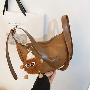 Brown PU leather crescent shoulder bag with plush charm and adjustable strap