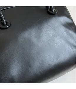 Close-up of minimalist black tote bag showing detailed lychee grain leather texture