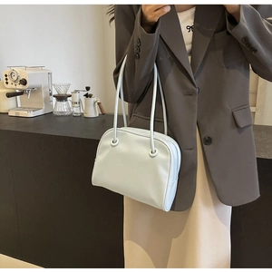 Close-up of a minimalist leather shoulder bag with unique ring strap details in a cafe