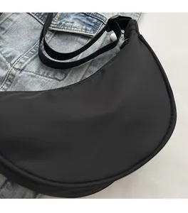 Gros plan sur un sac croissant en nylon noir avec bandoulière réglable et fermeture éclair