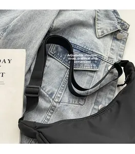 Détail de la bandoulière réglable d'un sac bandoulière noir en nylon avec fermeture