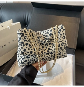 Détail d'un sac en toile imprimé léopard avec bandoulière chaîne dorée en boîte