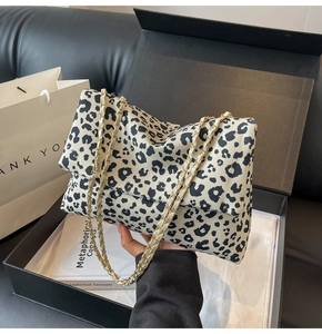 Détail macro du sac léopard avec bandoulière chaîne dorée dans un coffret cadeau chic