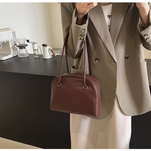 Detailed view of vintage dark brown faux leather tote bag worn by a model in a café