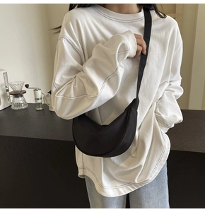 Sac bandoulière moderne en nylon noir porté par un mannequin dans un intérieur minimal