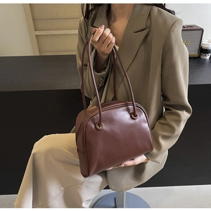 Detailed view of a dark brown vintage leather bowling bag styled for a professional office look
