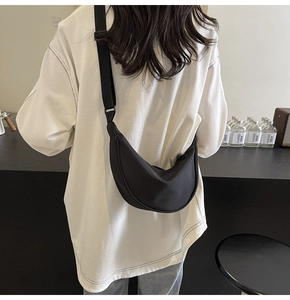 Vue arrière d'un sac bandoulière croissant en nylon noir porté par un mannequin en décor