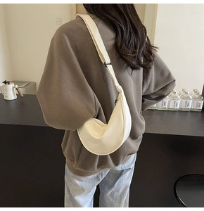 Vue latérale d'un sac bandoulière croissant beige en nylon sur un mannequin au café