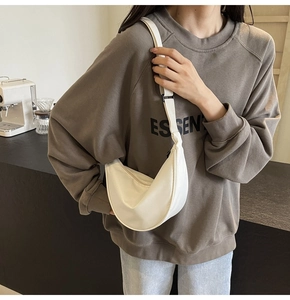 Détail d'un sac bandoulière en nylon blanc crème en forme de croissant porté par un mannequin