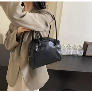 Detail of minimalist black leather tote bag with gold zipper and dual shoulder straps