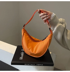 Détail d'un sac bandoulière orange en nylon en forme de croissant avec sangle réglable
