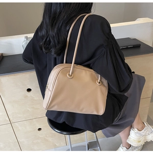 Detail view of a beige faux leather hobo shoulder bag with slim straps and sleek finish