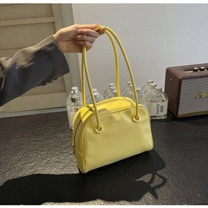 Detail of a bright yellow leather tote bag held by a model in a retro setting