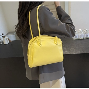 Detailed view of the yellow minimalist square shoulder bag shown on a female model