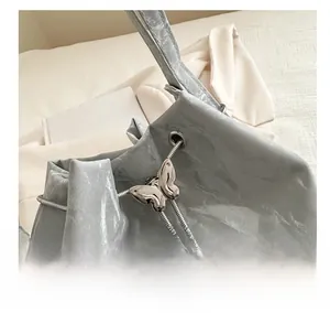 Détail du sac seau bleu clair avec boucle papillon argentée et cordon en chaîne métal