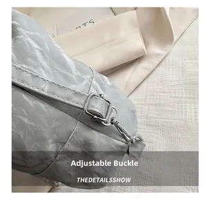 Gros plan sur la boucle métallique et les détails argentés du sac seau texturé