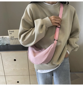 Modèle portant un sac bandoulière demi-lune en nylon rose avec sangle réglable au style décontracté