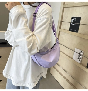 Détail d'un sac bandoulière croissant en nylon lavande léger porté par un mannequin