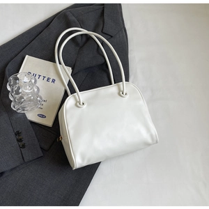Detailed close-up of white minimalist leather tote bag with elegant gold zipper and straps