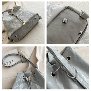 Vue détaillée du sac seau avec cordon papillon, breloque perle et pieds de protection métal