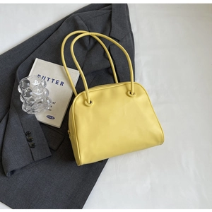Detailed top view of a minimalist yellow shoulder bag paired with a grey suit jacket