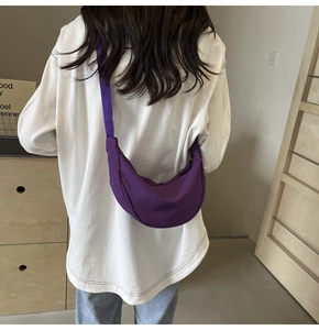 Vue mannequin montrant le sac bandoulière croissant en nylon violet porté à l'épaule