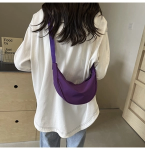 Mannequin portant un sac bandoulière croissant en nylon violet dans un décor minimaliste