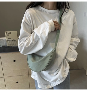 Détail du sac bandoulière croissant en nylon vert clair avec sangle sur un modèle