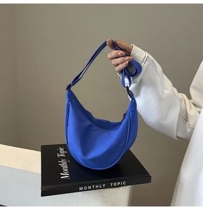 Détails d'un sac demi-lune en nylon bleu vif avec bandoulière réglable et fermeture éclair