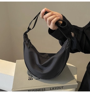 Détail d'un sac en nylon noir en forme de croissant avec bandoulière réglable sur décor