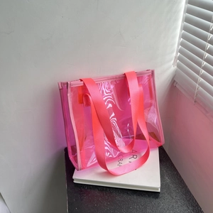 Pink translucent PVC tote bag with matching wide nylon shoulder strap and modern design