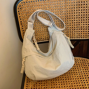 Schicke hellgraue Nylon-Mondtasche mit Plissee-Stoff auf einem Vintage-Rattanstuhl
