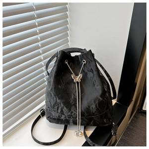 Détail du sac à dos seau noir avec cordon, fermoir papillon en métal et perles décoratives