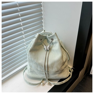 Détail du sac à dos seau vert menthe avec papillon métallique et cordon à perles