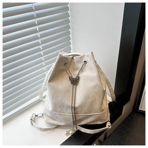 Détail du sac seau crème avec texture marbrée et fermoir papillon sur le cordon de serrage