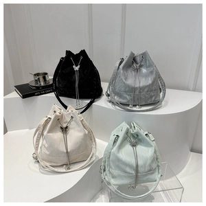 Détail de quatre sacs seaux en noir, argent, beige et vert avec perles et charm papillon