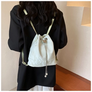 Detail of white pleated bucket backpack with butterfly charm and pearl drawstring chain