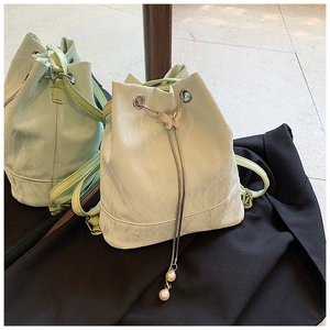 Detail of mint green bucket bag featuring pleated texture and pearl drawstring charms