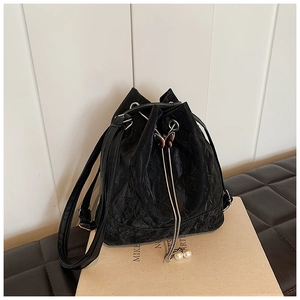 Detail of black pleated bucket bag with butterfly buckle and pearl drawstring