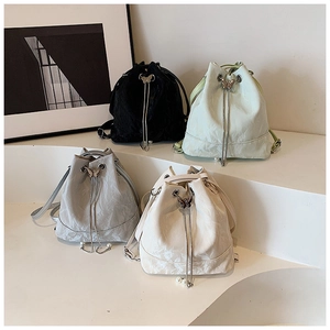 Detail of multi-color drawstring bucket bags featuring metallic butterfly and pearl charms