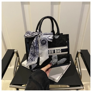 Détail d'un sac cabas noir avec broderie florale et foulard en soie décoratif