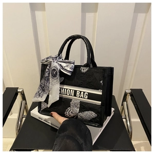 Détail du sac cabas brodé noir avec motifs papillon blancs et décor d'écharpe en soie
