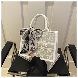 Détail du sac cabas floral avec un foulard décoratif en soie sur la poignée
