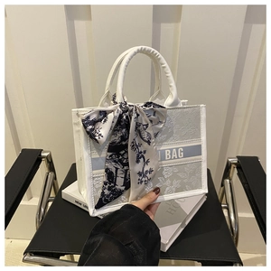 Vue détaillée du sac cabas blanc à gaufrage floral avec foulard en soie bleu et texte BAG