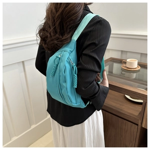Detail of teal nylon crossbody chest bag with metal zipper and woven decorative puller