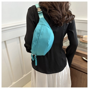 Back view of a model wearing a turquoise nylon crossbody chest bag with adjustable strap