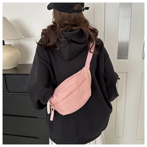 Detail view of pink canvas crossbody chest bag with woven zipper pullers and nylon strap