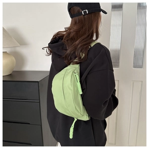 Detail of light green canvas fanny pack with braided cord zipper pull on model