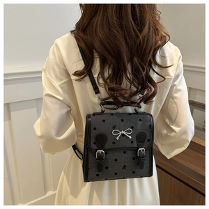 Detailed view of grey polka dot canvas backpack with silver bow buckle on model