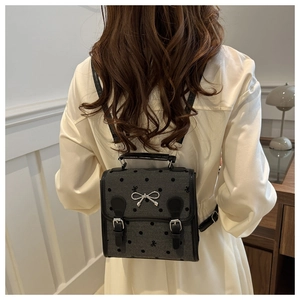 Detail of grey polka dot mini backpack with silver bow and leather strap closure